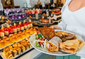 Woman,Holding,A,Plate,Full,Of,Food.,All,Inclusive,Concept. Why Curacao All Inclusive Resorts Might Not Be Your Best Bet; Eat like a traveler instead of a tourist.